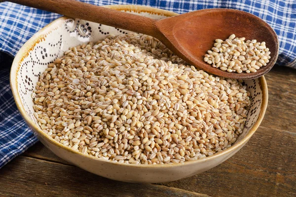 Barley in bowl on wooden board — Stock Photo, Image