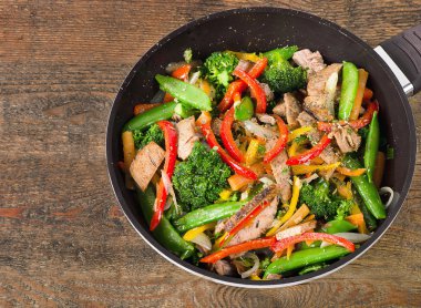 Beef and vegetables stir fry on table clipart