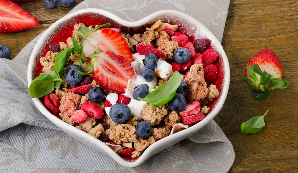 Muesli with berries in heart shaped bowl — Stock Photo, Image