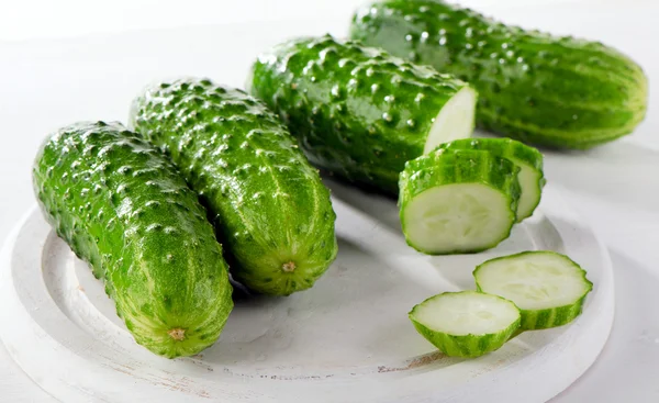 Fresh cucumbers on white cutting board. — Stock Photo, Image