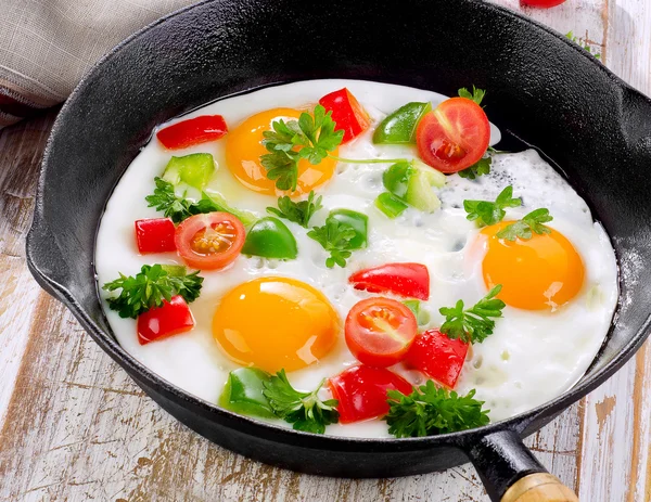 Fried eggs in pan with vegetables — Stock Photo, Image