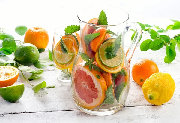 Pitcher and glass with citrus fruits — Stock Photo, Image