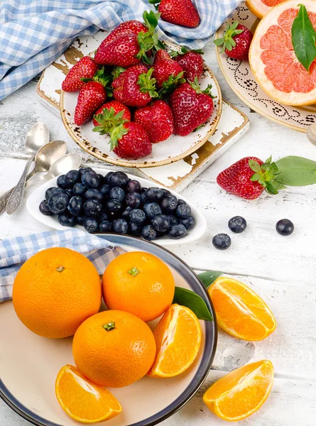 Frutas e bagas frescas em uma tábua de madeira branca . — Fotografia de Stock