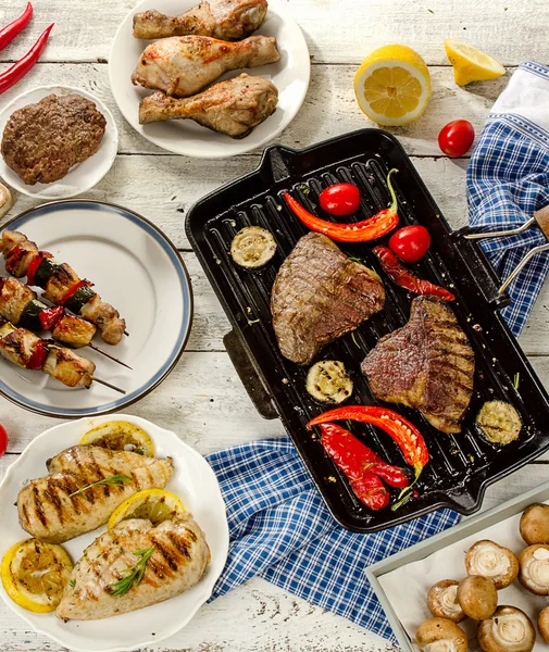 Carnes a la parrilla con verduras sobre tabla de madera blanca . — Foto de Stock