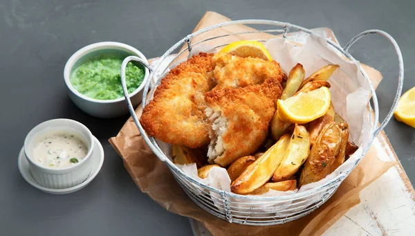 British traditional cuisine fish and chips. Served with mashed peas and different sauces.