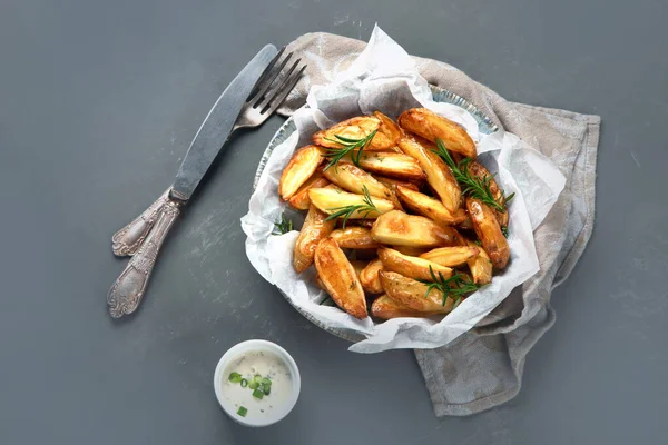 Baked country style potato wedges with herbs and sauce.