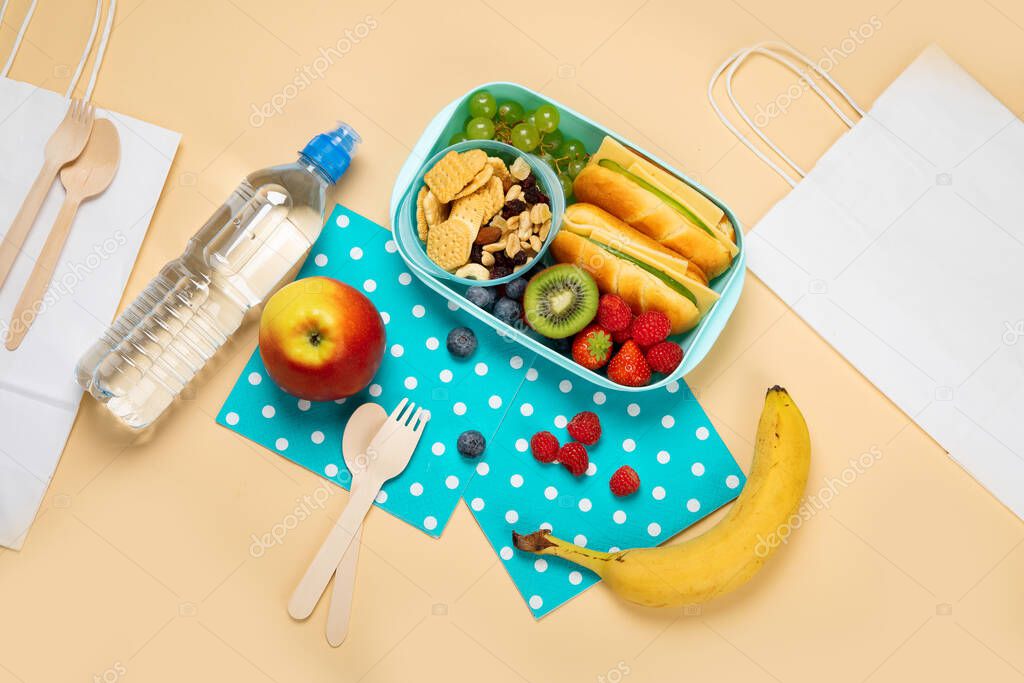 School lunch box with sandwiches, vegetables and fruits on orange background. Top view, copy space