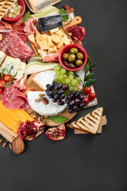 Aperatif masası. Koyu arka planda peynir, fuit ve et panosu. Üst görünüm, Spac kopyala