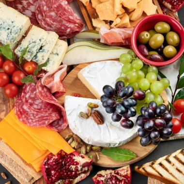 Aperatif masası. Koyu arka planda peynir, fuit ve et panosu. Üst görünüm