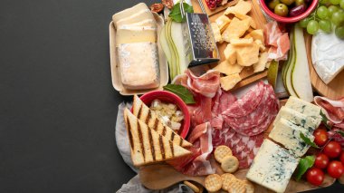 Aperatif masası. Koyu arka planda peynir, fuit ve et panosu. Üst görünüm, Spac kopyala