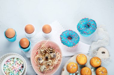 Yumurtalı Paskalya kompozisyonu ve açık gri arka planda renkli tatlılar. Mevsimlik tatil konsepti. Üst görünüm, alanı kopyala