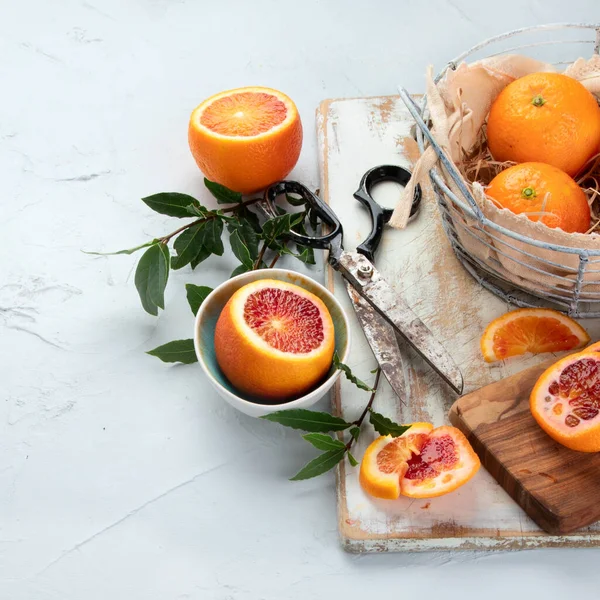 Oranges with leaves in basket, orange juice on light background. Copy space