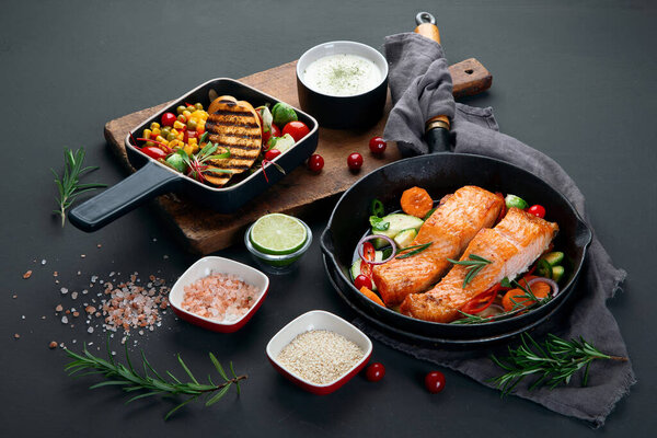Homemade fresh salmon with starter and vegetables on dark background. 