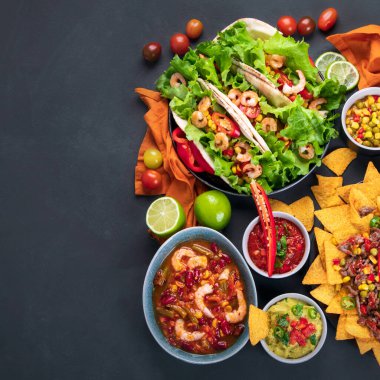 Lezzetli İspanyol Meksika yemeği tahtası. Nachos, taco, guacamole, karides, avokado ve yıldız meyvesi. Acı ve baharatlı. Üst görünüm, alanı kopyala