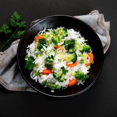 Taze ve sağlıklı vegan pirinç kasesi brokoli, havuç ve yanında çubuklarla taze soğan ile servis edilir. Karanlık arka plan. Üst görünüm