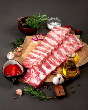 Koyu arkaplanda baharatla tatlandırılmış taze çiğ domuz pirzolası.. 