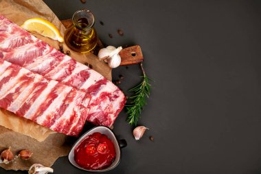 Koyu arkaplanda baharatla tatlandırılmış taze çiğ domuz pirzolası. Üst görünüm, Spac kopyala
