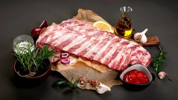 Koyu arkaplanda baharatla tatlandırılmış taze çiğ domuz pirzolası.. 