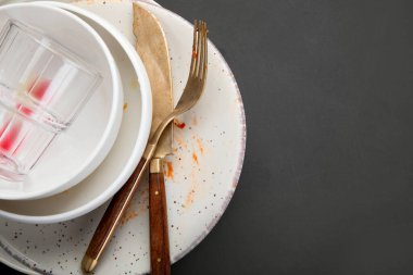Koyu arkaplanda yemek artıkları olan boş ve kirli tabaklar yığını. Üst görünüm, alanı kopyala