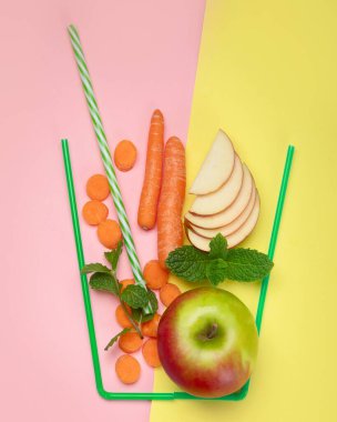 Renkli arka planda elma ve havuçtan yapılmış bir bardak. Minimalizm tasarım konsepti. Üst görünüm, Spac kopyala