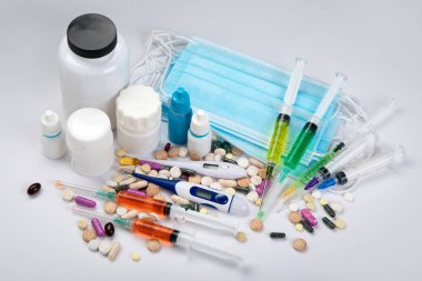 Maske, şırınga, farklı ilaç çeşitleri ve tıbbi şişeler. Hastalık ve tedavi kavramı. İlaç ve sağlık hizmetleri. 