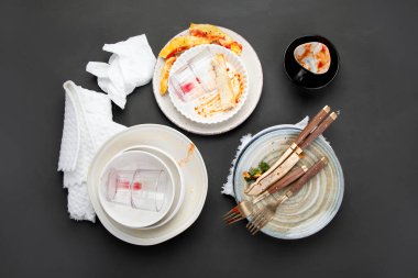 Koyu arkaplanda yemek artıkları olan boş ve kirli tabaklar yığını. Üst görünüm