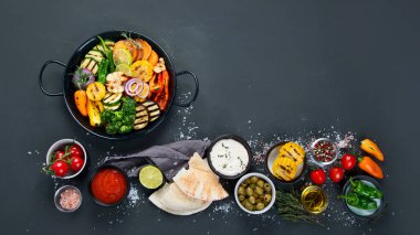 Izgara sebzeler, siyah arka planda dökme demir tavada. Izgara menüsü. Üst görünüm, alanı kopyala