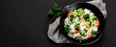 Taze ve sağlıklı vegan pirinç kasesi brokoli, havuç ve yanında çubuklarla taze soğan ile servis edilir. Karanlık arka plan. Üst görünüm, kopyalama alanı, panorama pankartı