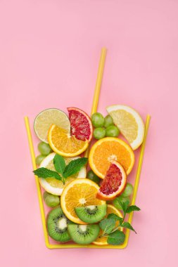 Renkli arka planda farklı meyvelerden yapılmış bir bardak. Minimalizm tasarım konsepti. Üst görünüm, alanı kopyala