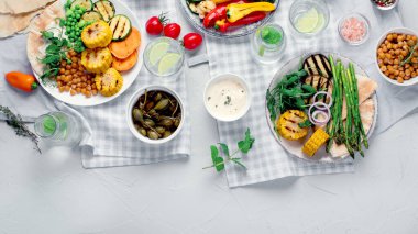 Açık gri arka planda servis edilen soslu ve abur cuburlu nefis ızgara sebzeler. Barbekü menüsü. Üst görünüm, alanı kopyala