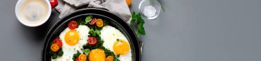Kahvaltıda ıspanaklı yumurta ve yanında kahve olan vişneli domates. Gri arka plan. Üst görünüm, kopyalama alanı, panorama bannesi