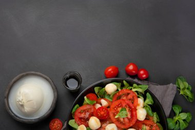 Dilimlenmiş domatesli İtalyan caprese salatası ve koyu arkaplanda mozzarela. Sağlıklı gıda konsepti. Üst görünüm, alanı kopyala