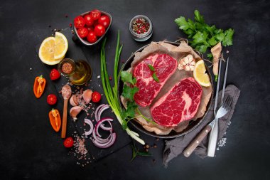 Baharatlı çiğ et ve koyu arkaplanda otlar. Sağlıklı gıda konsepti. Üst görünüm