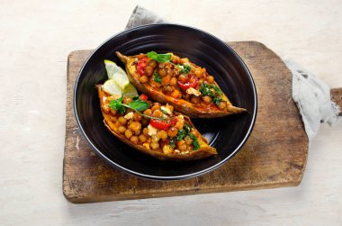 Baharatlı nohut, sos ve bitkilerle doldurulmuş tatlı patates. Ev yapımı vegan gıda konsepti. 