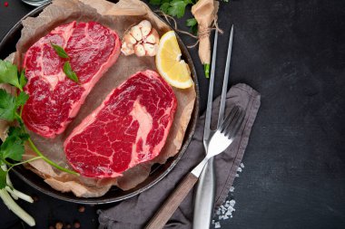 Baharatlı çiğ et ve koyu arkaplanda otlar. Sağlıklı gıda konsepti. Üst görünüm, alanı kopyala