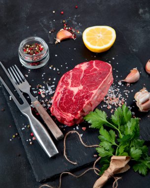 Baharatlı çiğ et ve koyu arkaplanda otlar. Sağlıklı gıda konsepti.