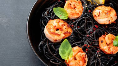 Karanlık arka planda karides ve parmesanlı spagetti. Lezzetli deniz ürünleri makarnası. Boşluğu kopyala