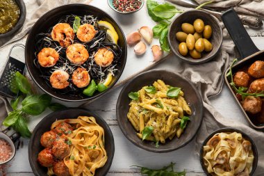 Beyaz ahşap arka planda akşam yemeği için geleneksel abur cubur ve soslu İtalyan makarnası çeşitleri. Ev yapımı yemek konsepti. Üst görünüm