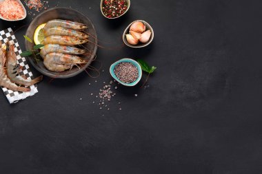 Siyah arka planda çiğ beyaz karidesler. Taze deniz ürünleri konsepti. Üst görünüm, alanı kopyala