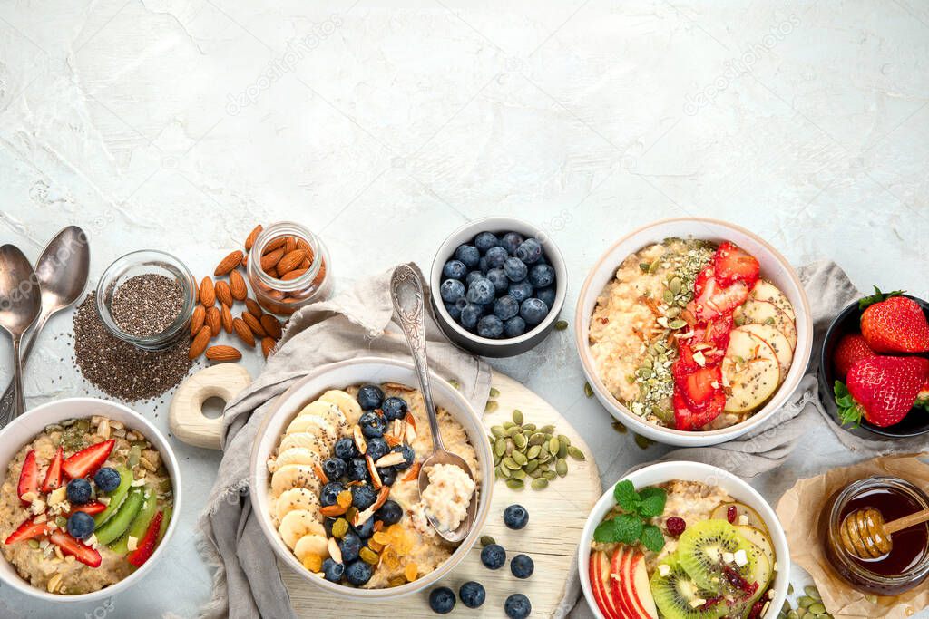 Oatmeal bowls with delicious fruits and fresh berries on light background. Healthy breakfast concept. Top view, copy space