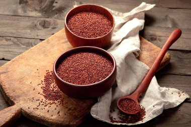 Red quinoa seeds on wooden background. Healthy vegan food concept. Top view