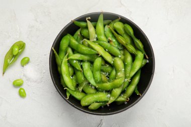 Çiğ edamame soya fasulyesi, açık gri arka planda tuz ve sos. Üst görünüm