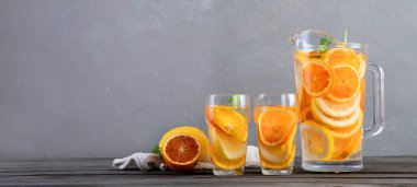 Refreshing orange lemonade on grey wooden table. Summer drinks concept. Copy space, panorama. front view