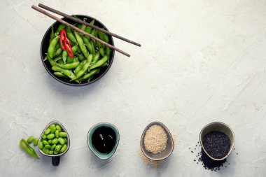 Çiğ edamame soya fasulyesi, açık gri arka planda tuz ve sos. Üst görünüm, alanı kopyala