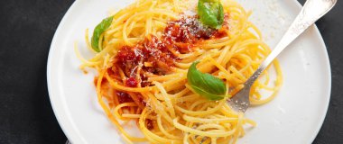 Lezzetli İtalyan makarnası domates soslu, parmesanlı ve fesleğenli gri arka planda.. 