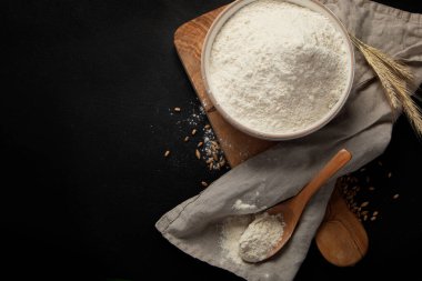 Wheat flour on dark background. Food preparing concept. Top view, copy space