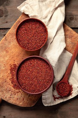 Red quinoa seeds on wooden background. Healthy vegan food concept. Top view