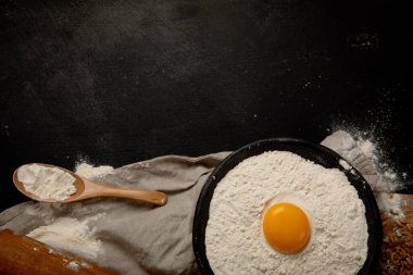 Wheat flour on dark background. Food preparing concept. Top view, copy space