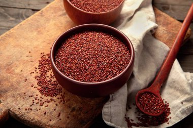 Red quinoa seeds on wooden background. Healthy vegan food concept. 