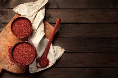 Red quinoa seeds on wooden background. Healthy vegan food concept. Top view, copy space